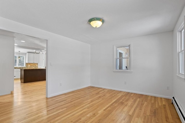 spare room featuring light wood-style floors, baseboards, and baseboard heating