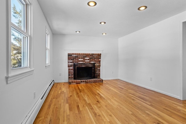 unfurnished living room featuring baseboards, light wood-style flooring, recessed lighting, a fireplace, and a baseboard heating unit