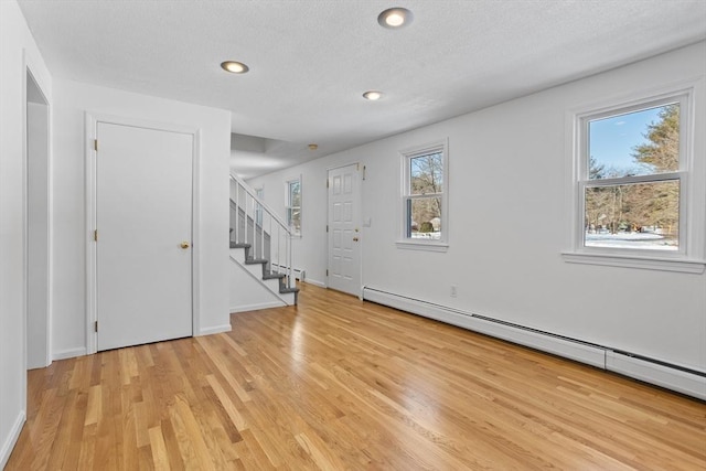 foyer featuring light wood finished floors, stairs, baseboard heating, recessed lighting, and a textured ceiling