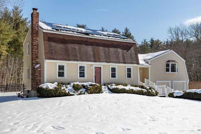 dutch colonial featuring roof mounted solar panels and a chimney