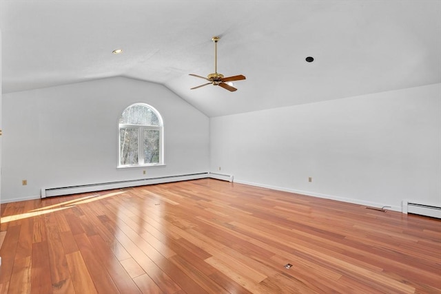 spare room with baseboards, vaulted ceiling, baseboard heating, light wood-style flooring, and a ceiling fan