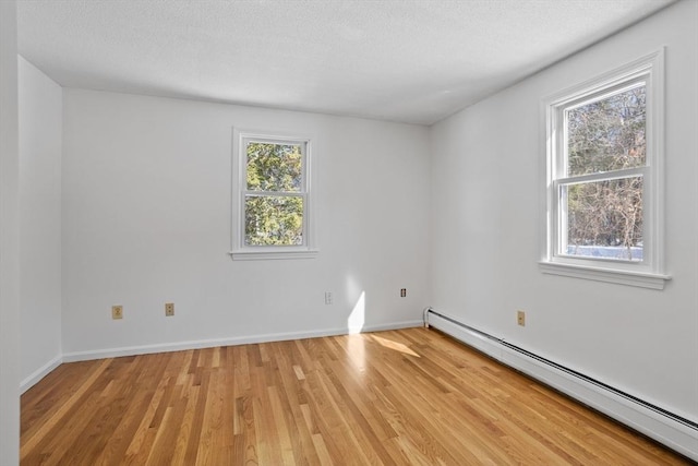 spare room with a textured ceiling, light wood-style flooring, baseboards, and a baseboard radiator