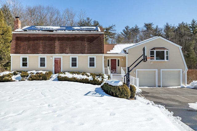 dutch colonial featuring an attached garage, a chimney, and driveway