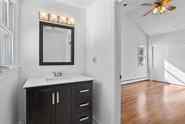 bathroom with vanity, wood finished floors, ceiling fan, vaulted ceiling, and baseboard heating