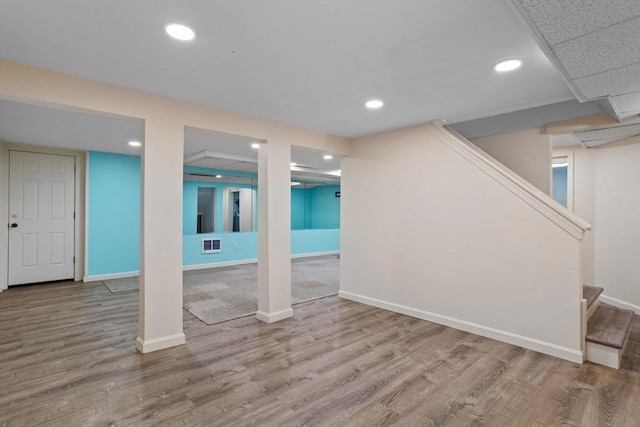 finished basement featuring visible vents, recessed lighting, stairs, and wood finished floors