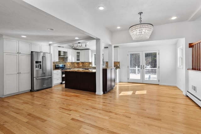 kitchen featuring tasteful backsplash, french doors, stainless steel appliances, white cabinetry, and wall chimney exhaust hood