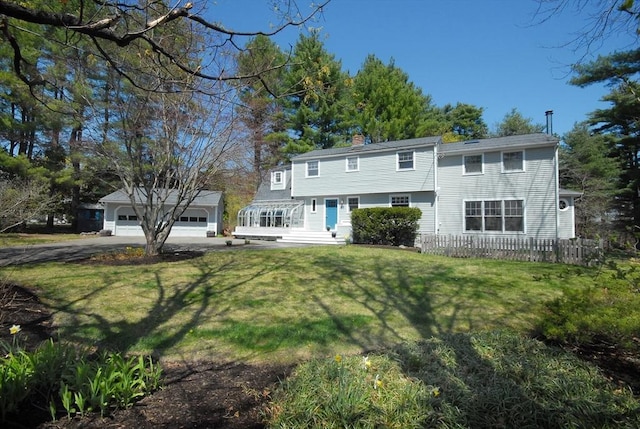 back of house with a lawn, fence, driveway, and a chimney