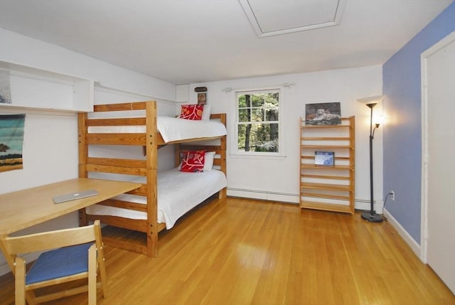 bedroom featuring a baseboard heating unit and wood finished floors