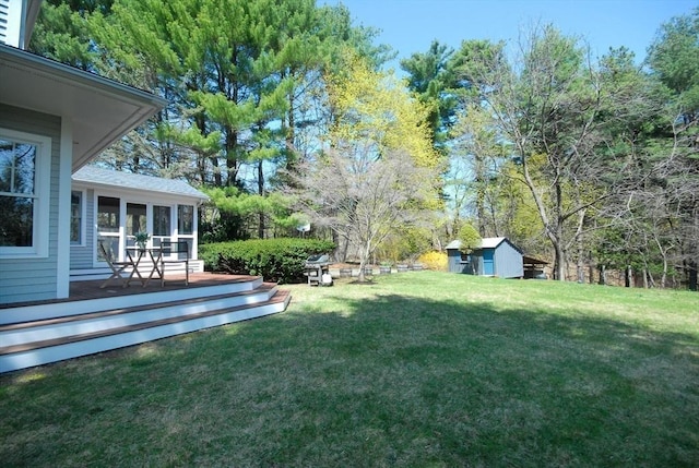 view of yard featuring a wooden deck, an outdoor structure, a sunroom, and a storage unit