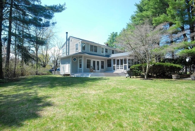 rear view of house featuring a yard and a sunroom