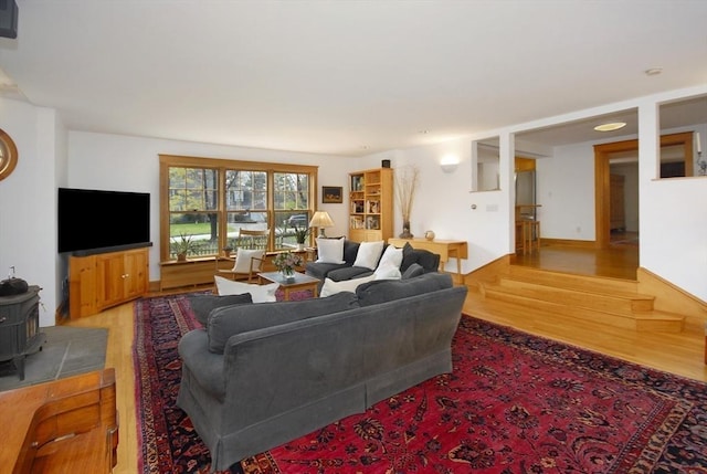 living room featuring a wood stove, stairs, and wood finished floors