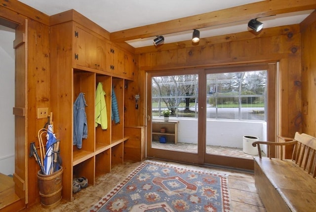mudroom featuring beamed ceiling, wood walls, and plenty of natural light