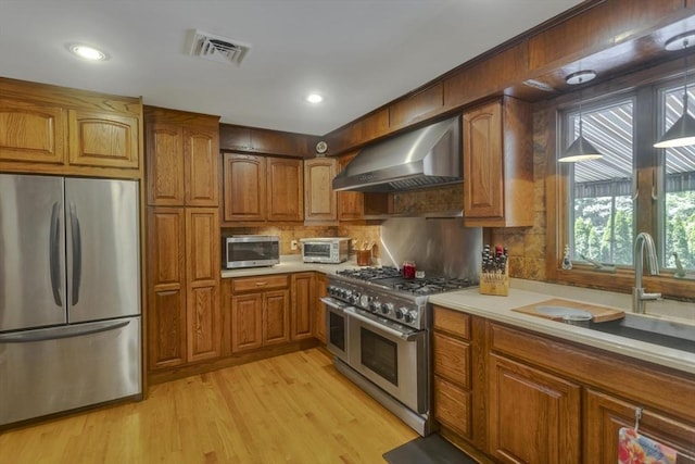 198 Mountain View Dr, Holyoke, MA 01040 - kitchen with appliances with stainless steel finishes, wall chimney range hood, brown cabinets, light countertops, and recessed lighting