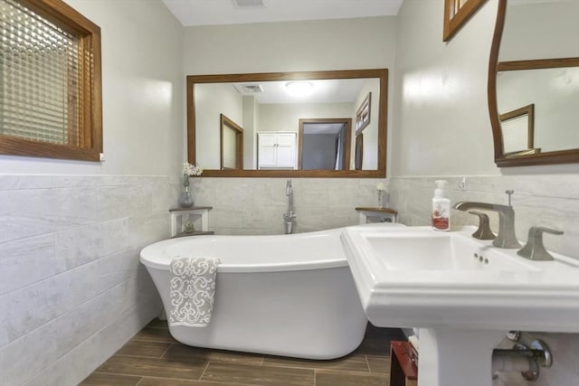 198 Mountain View Dr, Holyoke, MA 01040 - full bathroom with tile walls, a freestanding tub, a wainscoted wall, wood finished floors, and a sink
