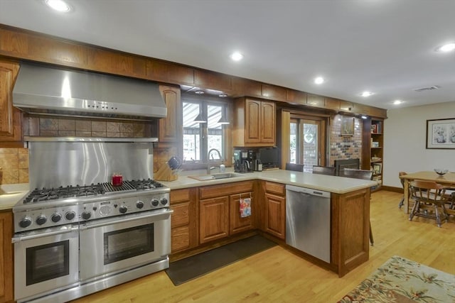 198 Mountain View Dr, Holyoke, MA 01040 - kitchen with wall chimney exhaust hood, appliances with stainless steel finishes, a sink, a peninsula, and light countertops