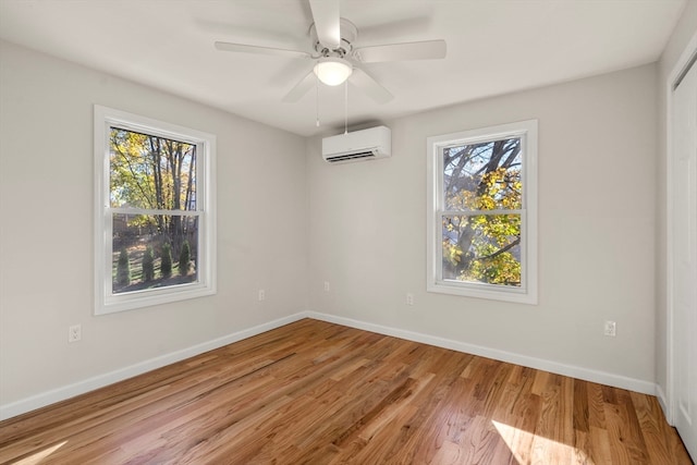 spare room with ceiling fan, light hardwood / wood-style floors, an AC wall unit, and a wealth of natural light