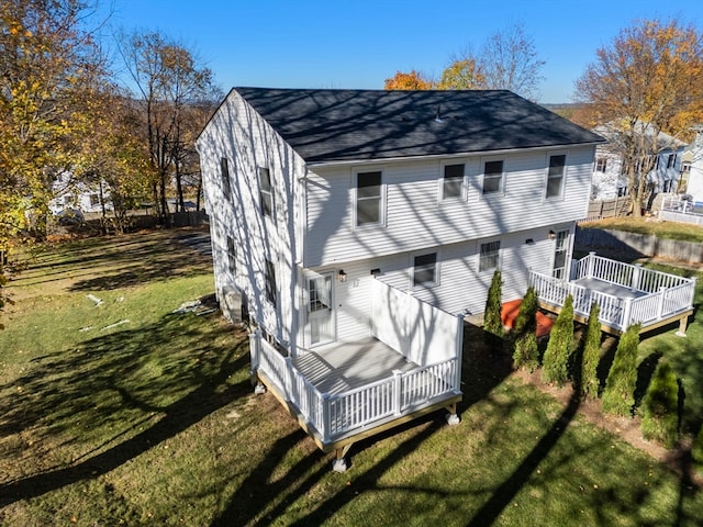 rear view of house featuring a lawn and a deck