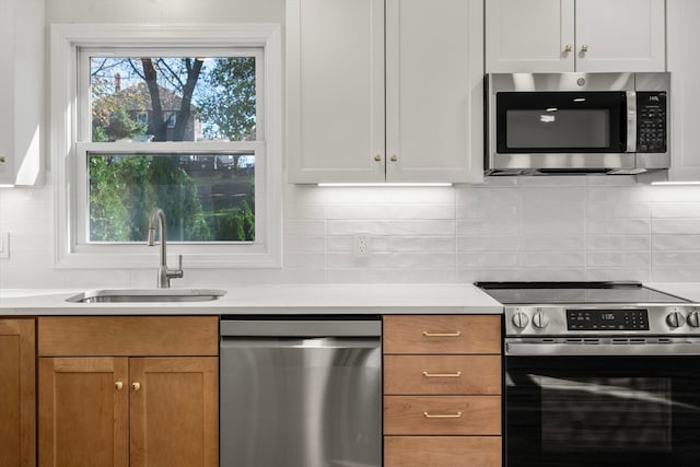 kitchen featuring tasteful backsplash, sink, white cabinets, and stainless steel appliances