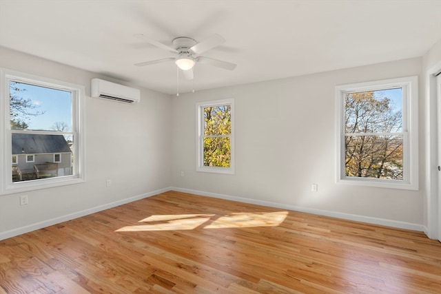 unfurnished room featuring a wall mounted air conditioner, light hardwood / wood-style flooring, and ceiling fan