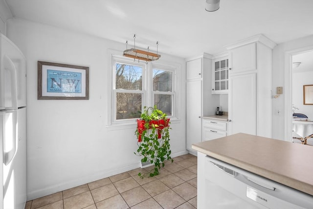 kitchen featuring light tile patterned floors, light countertops, glass insert cabinets, white cabinetry, and white appliances