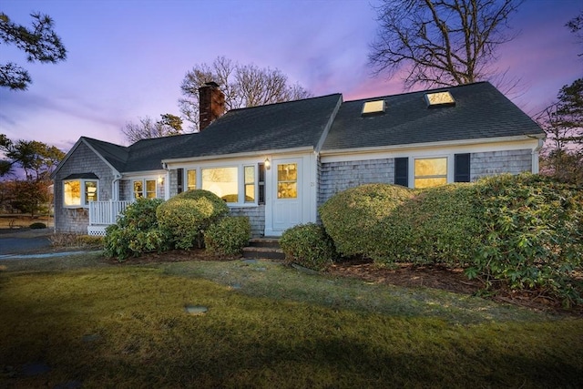 view of front of house featuring a shingled roof, a yard, and a chimney