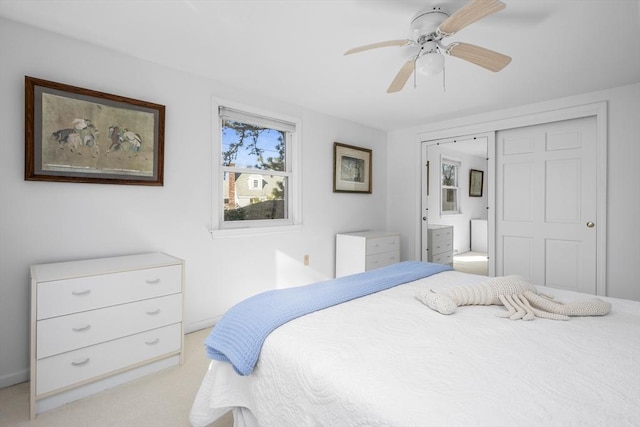 bedroom featuring light carpet, ceiling fan, and ensuite bathroom