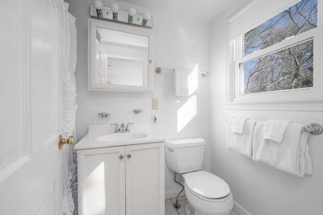 bathroom featuring toilet, vanity, and baseboards