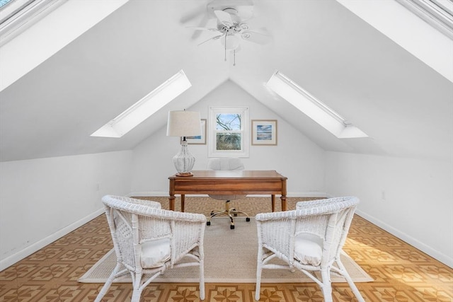 unfurnished office with lofted ceiling with skylight, baseboards, and a ceiling fan