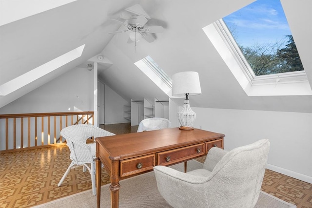 office area featuring ceiling fan, vaulted ceiling with skylight, and baseboards