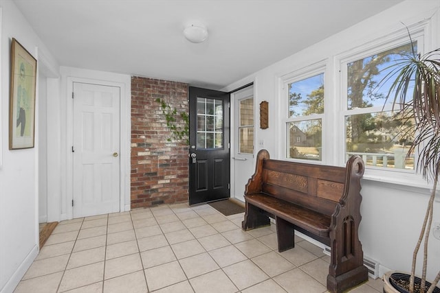 entryway with brick wall, a wealth of natural light, and light tile patterned flooring