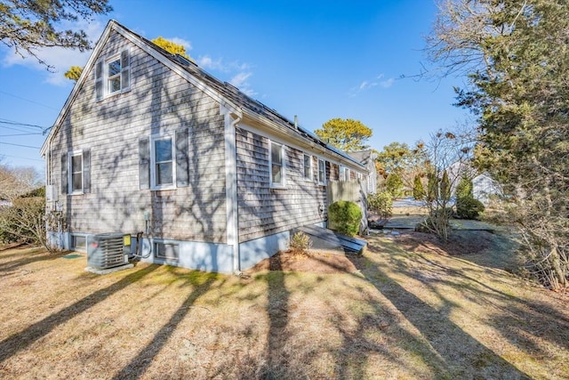 view of side of property with central AC unit and a lawn