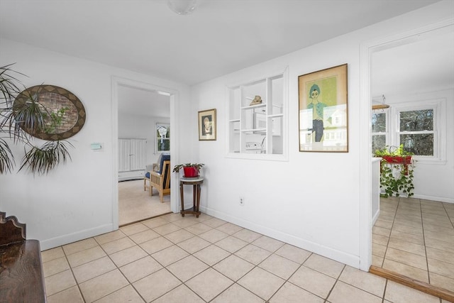 spare room featuring light tile patterned floors, built in shelves, and baseboards