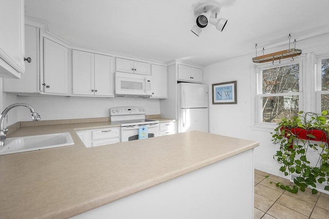 kitchen with white appliances, white cabinets, a peninsula, light countertops, and a sink