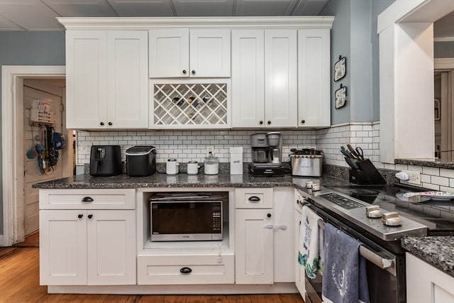 kitchen with stainless steel appliances, white cabinets, and light hardwood / wood-style floors