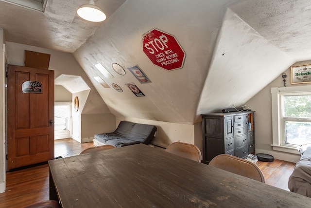 bonus room with lofted ceiling, hardwood / wood-style flooring, and a textured ceiling