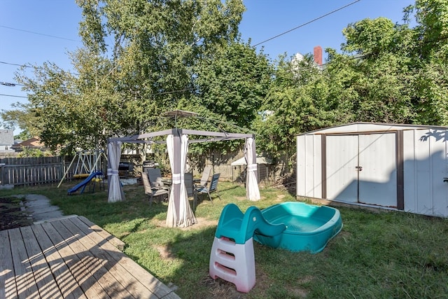 view of yard featuring a wooden deck, a shed, a gazebo, and a playground