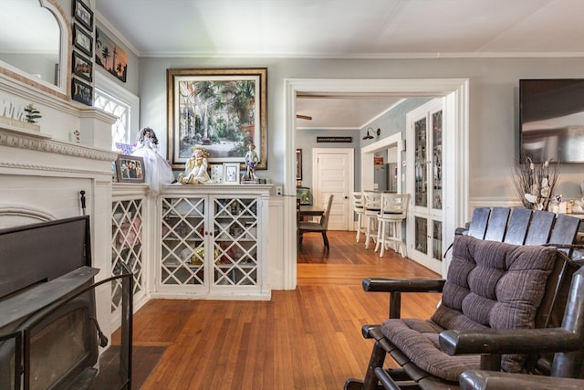 sitting room with ornamental molding and wood-type flooring