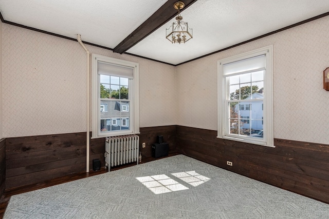 spare room with radiator heating unit, wooden walls, a textured ceiling, and hardwood / wood-style floors