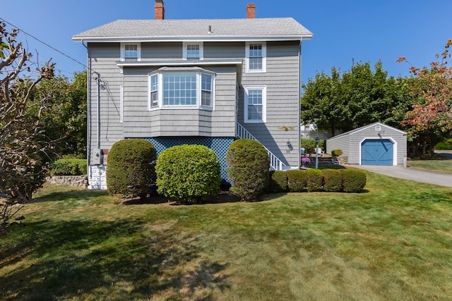 view of front of property with an outbuilding, a garage, and a front lawn