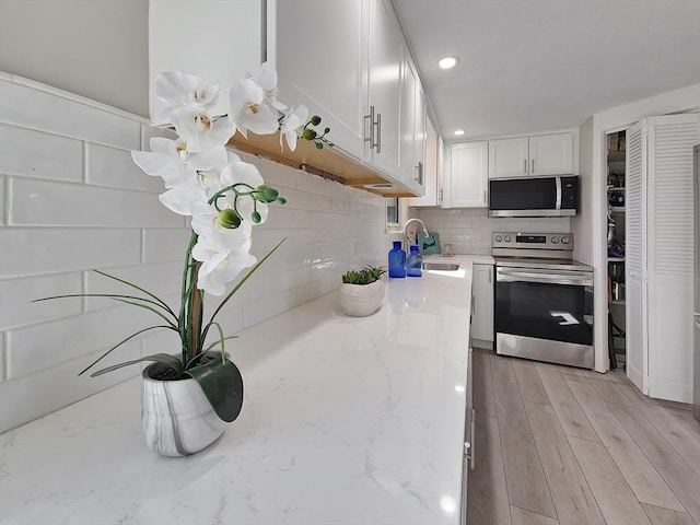 11 Great Oak Rd, Brewster, MA 02631 - kitchen with a sink, white cabinetry, tasteful backsplash, light wood-type flooring, and stainless steel appliances