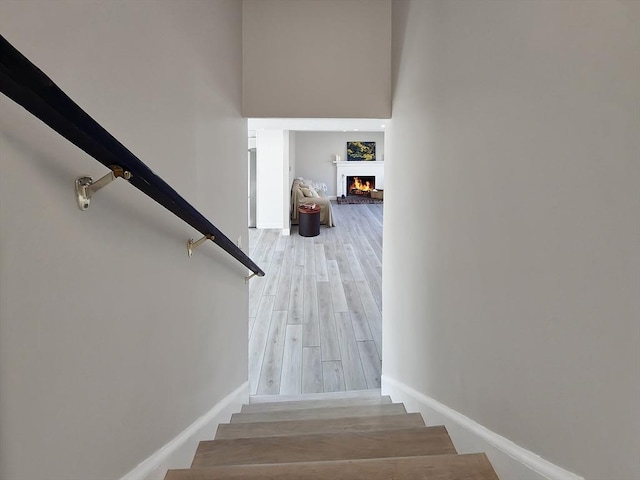 11 Great Oak Rd, Brewster, MA 02631 - staircase with a warm lit fireplace, baseboards, a towering ceiling, and wood finished floors