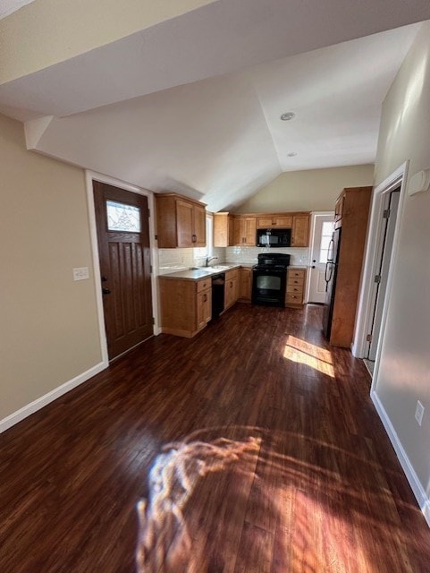 kitchen with dark wood-type flooring, vaulted ceiling, decorative backsplash, and black appliances