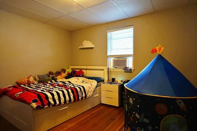 bedroom with cooling unit, a paneled ceiling, and wood finished floors