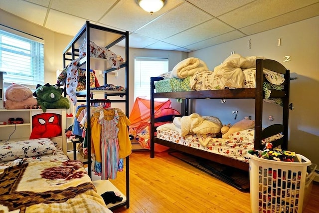 bedroom with a paneled ceiling, multiple windows, and wood finished floors