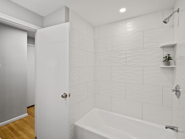 bathroom with hardwood / wood-style flooring and tiled shower / bath