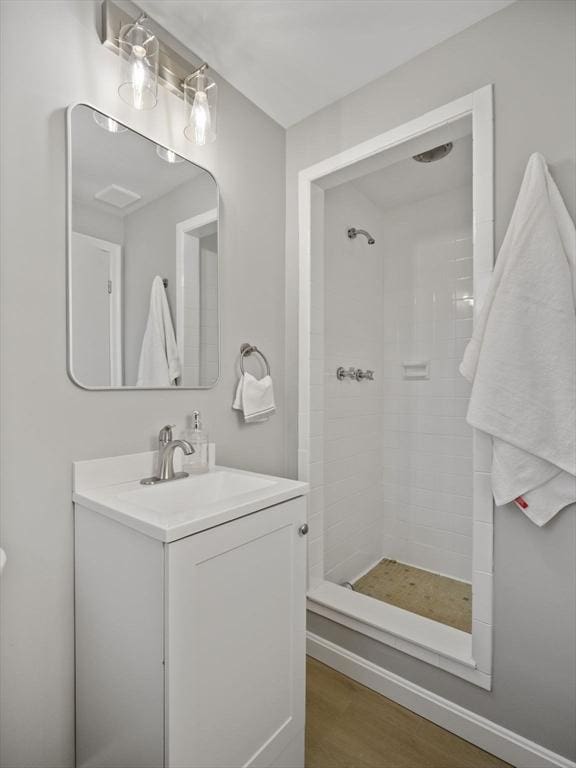 bathroom featuring wood-type flooring, vanity, and a tile shower