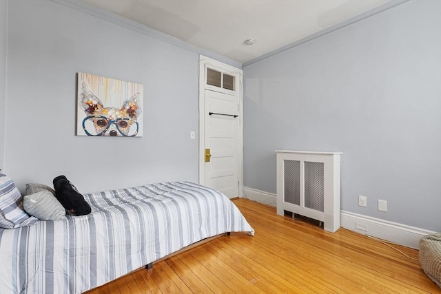 bedroom featuring light wood-style floors, baseboards, and radiator heating unit