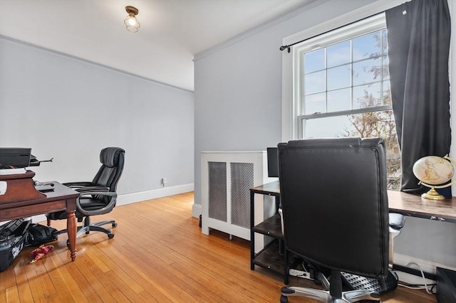 home office featuring crown molding, baseboards, hardwood / wood-style floors, and radiator