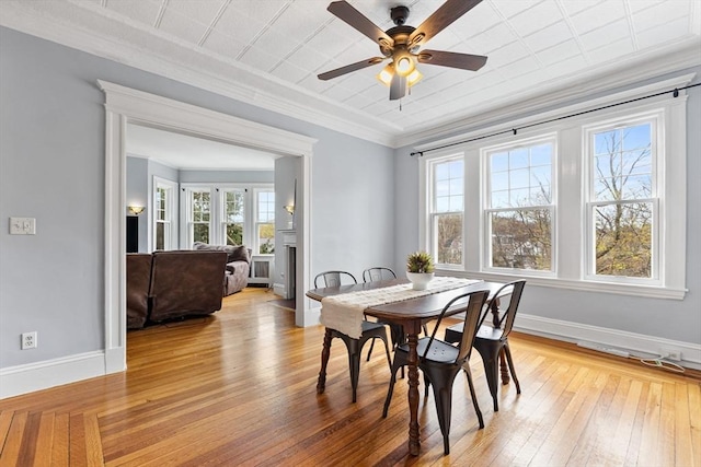 dining area with crown molding, a ceiling fan, baseboards, and light wood finished floors