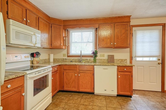 kitchen with white appliances, brown cabinets, and a sink